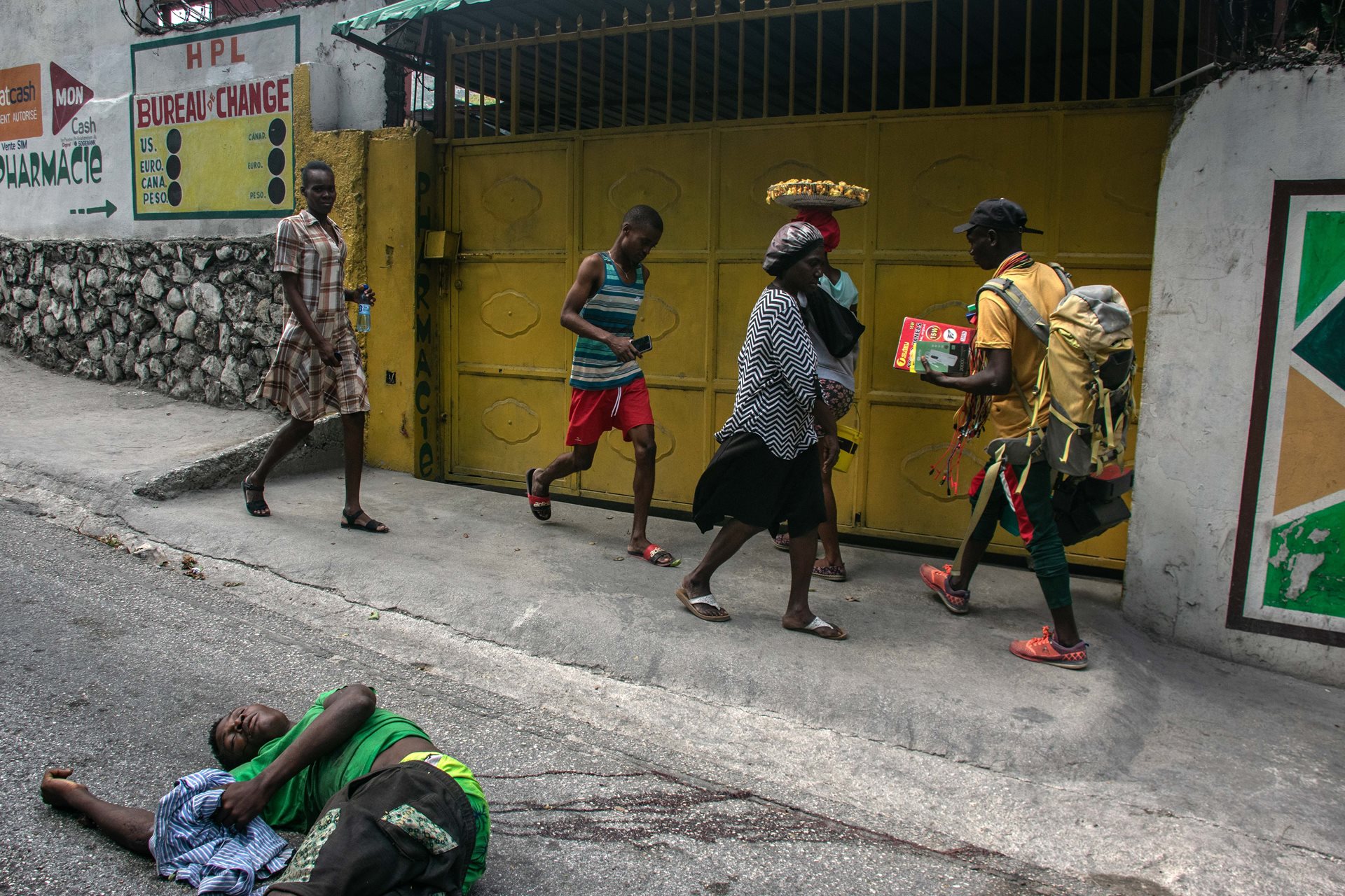 People walk past the body of a man shot and killed by unidentified men the night before, in Port-au-Prince, Haiti.