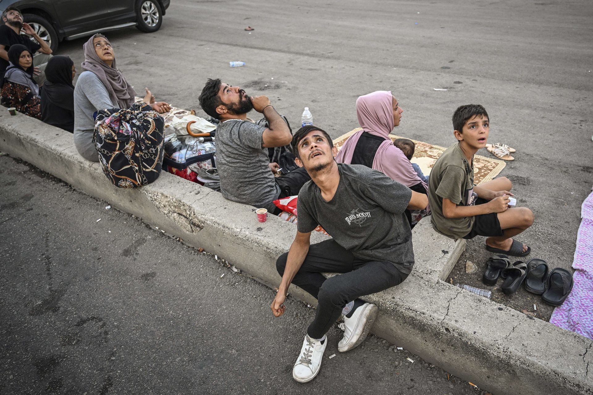 People glance anxiously upwards during an Israeli drone strike, as they take refuge away from buildings in Beirut's Dahiyeh neighborhood, Lebanon. Jets and drones often fly at low altitudes, causing fear and distress.<br />
&nbsp;